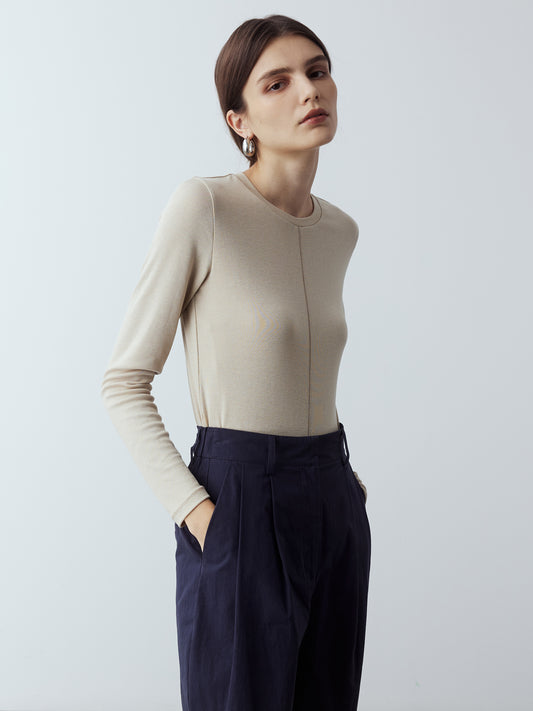 Model is wearing the Fitted Long Sleeve T-Shirt in Sand, which comes with a rounded crew neckline and a centre front stitch line. Arm-hugging but gives a relaxed bodice. Worn with Cotton Tailored Trousers in Navy.