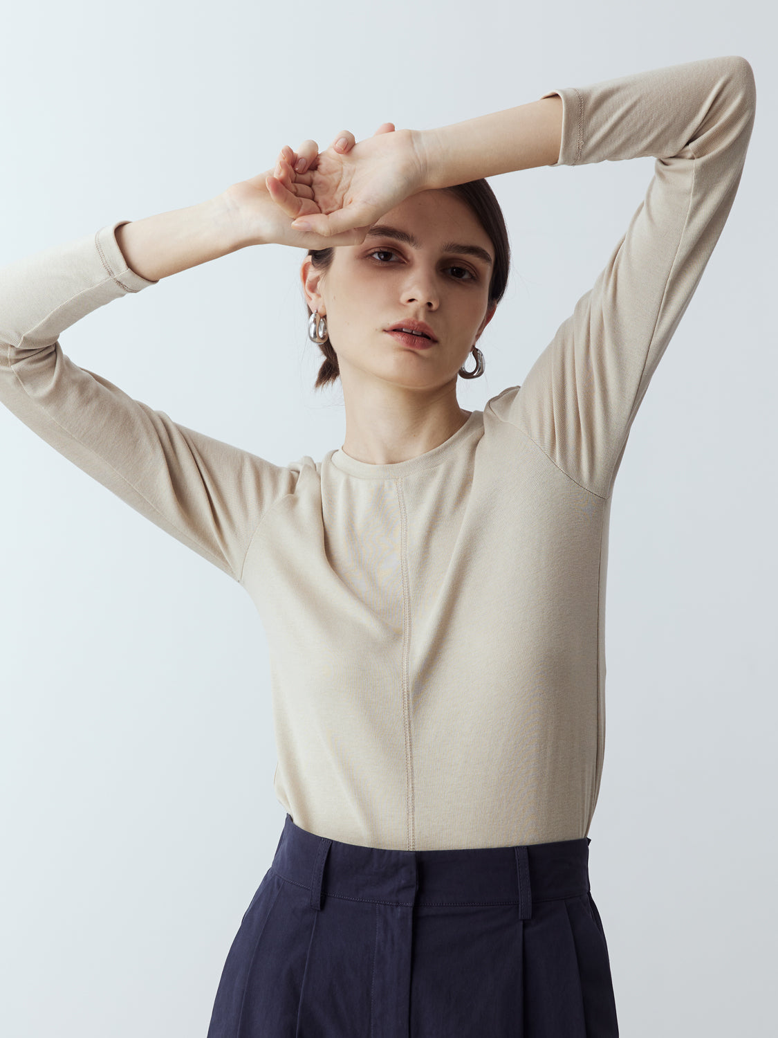 sand : Model is wearing the Fitted Long Sleeve T-Shirt in Sand, which comes with a rounded crew neckline and a centre front stitch line. Arm-hugging but gives a relaxed bodice. Worn with Cotton Tailored Trousers in Navy.