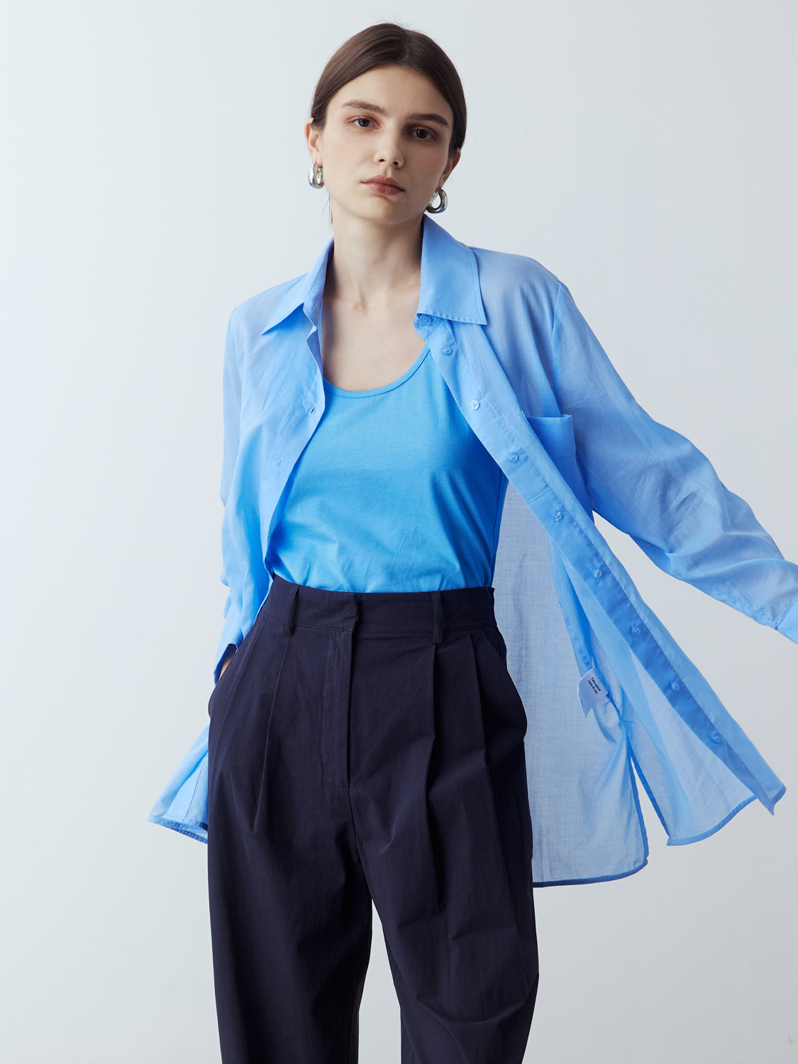 light blue : Model is wearing the Sheer Long Sleeve Shirt in Light Blue, which comes with a straight hem, front placket with buttons and a left breast pocket. Worn with the Jersey Tank in Light Blue, the Cotton Tailored Trousers in Navy and metallic silver heels.