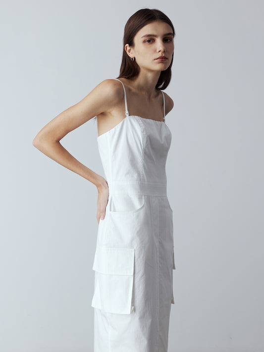 Model is wearing the Adjustable Cargo Dress in White, which comes with back pockets, and cargo and slash pockets at the sides. This is a sleeveless garment with spaghetti straps. Can also be worn as a tube dress. Worn with silver heels.