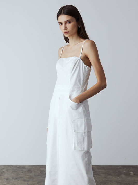 Model is wearing the Adjustable Cargo Dress in White, which comes with back pockets, and cargo and slash pockets at the sides. This is a sleeveless garment with spaghetti straps. Can also be worn as a tube dress. Worn with silver heels.